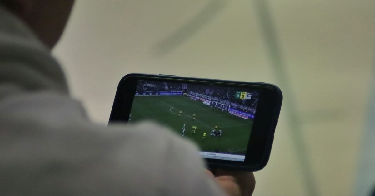 Una persona mira un partido de fútbol en la pantalla de su celular.