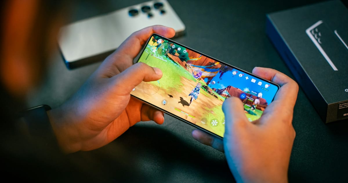 Dos manos sostienen un celular en horizontal con un juego de acción en la pantalla.