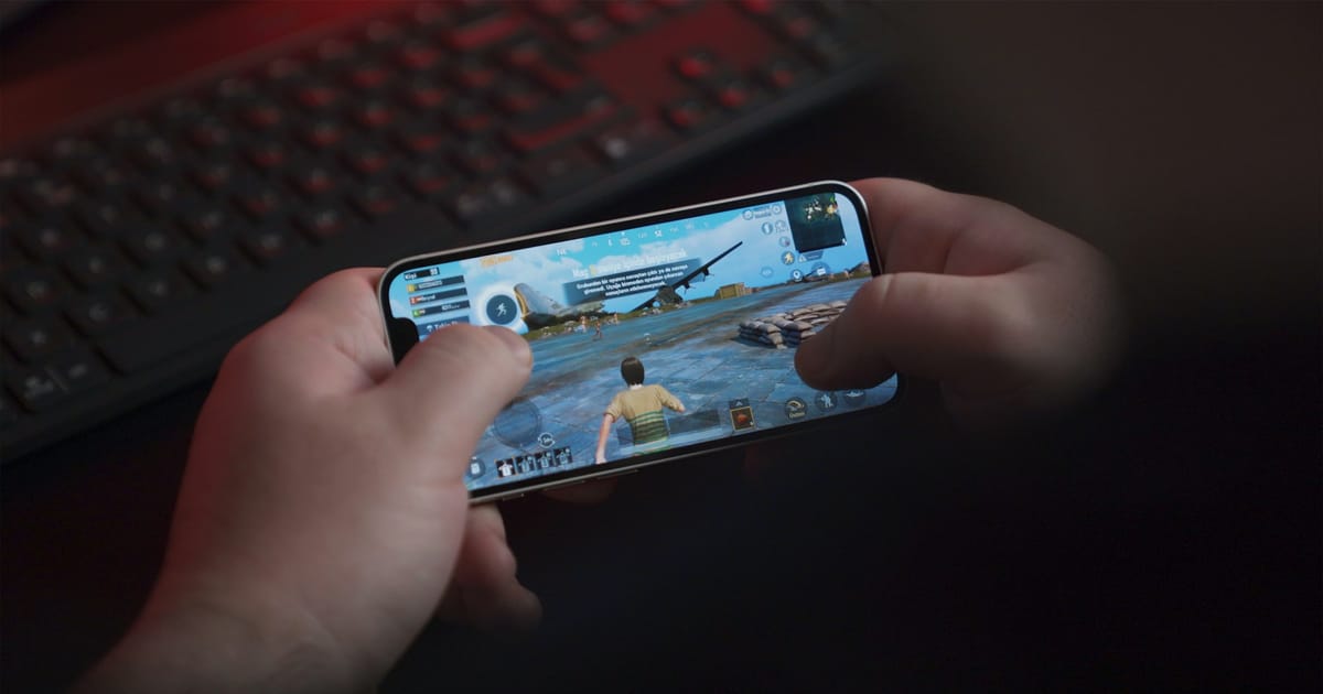 Una persona sostiene un celular Android negro con las dos manos.
