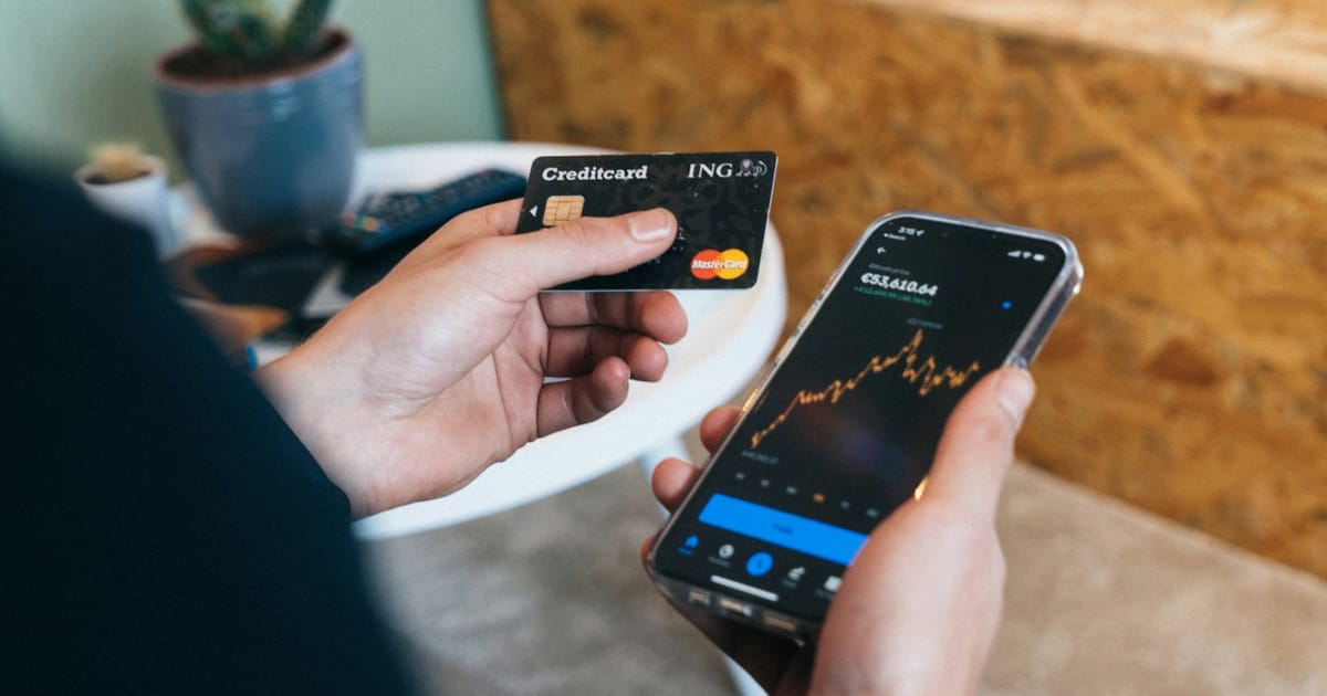 Una persona sostiene su celular y una tarjeta para una compra en línea.