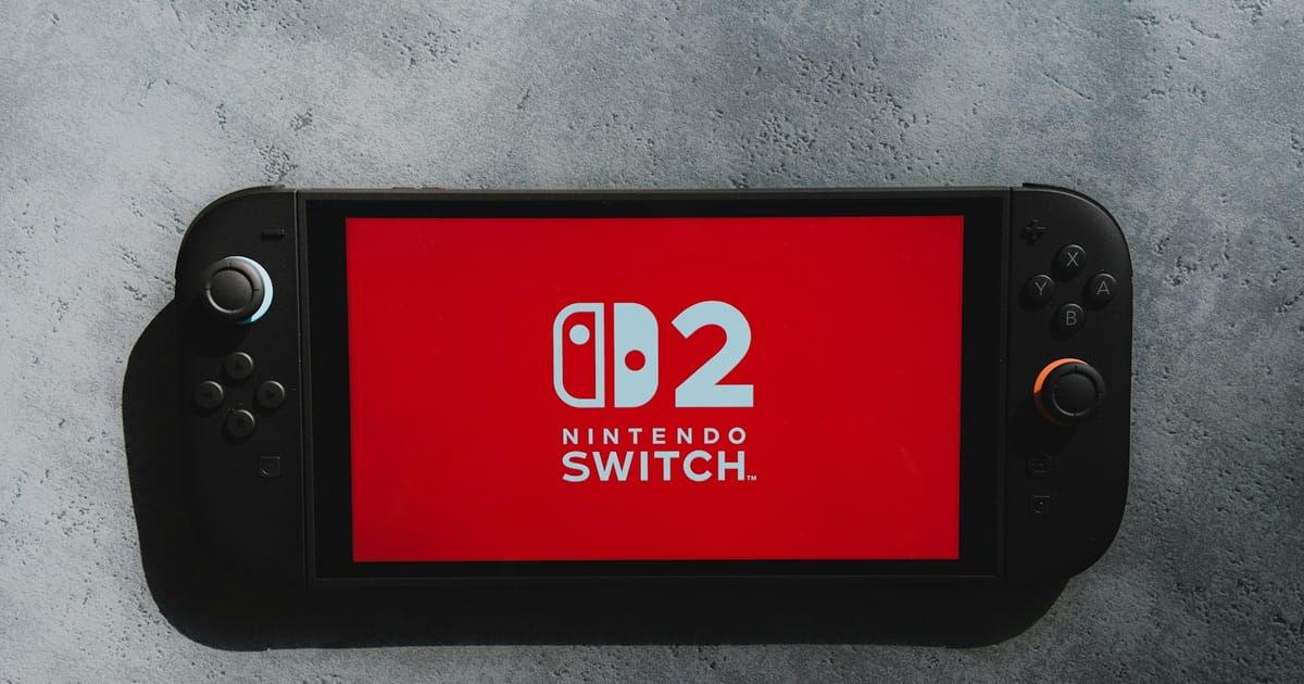 Una consola Nintendo Switch 2 con el logotipo en rojo en la pantalla, sobre una superficie gris.