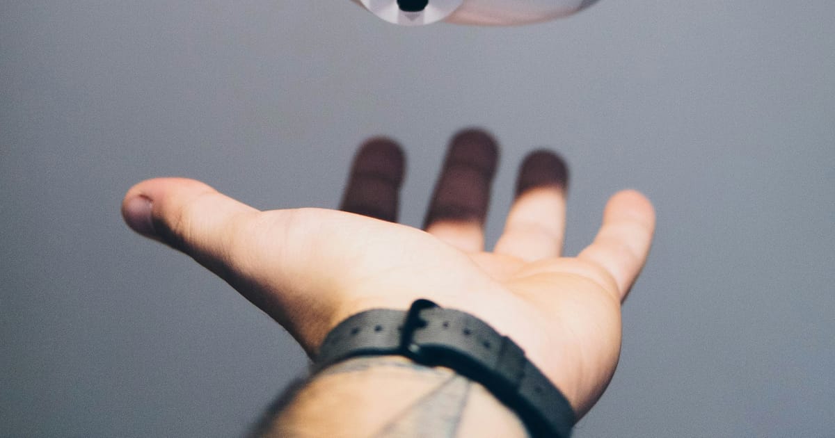 Un control DualShock de PlayStation sobre la palma de una mano.