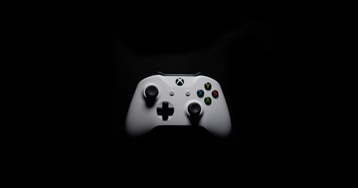 Un control blanco de Xbox iluminado sobre fondo oscuro.