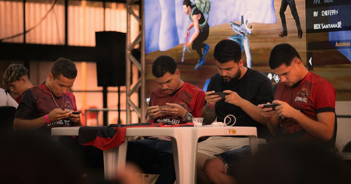 Un equipo de esports con camisetas iguales juega en celulares durante una competencia.