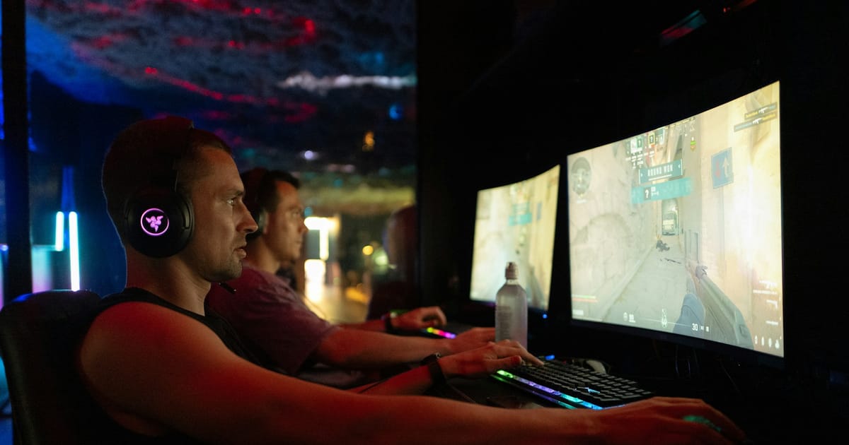 Dos jugadores compiten frente a computadoras en un evento de esports.