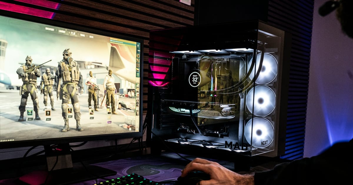 Una persona juega un shooter en un monitor junto a una PC con luces de colores.