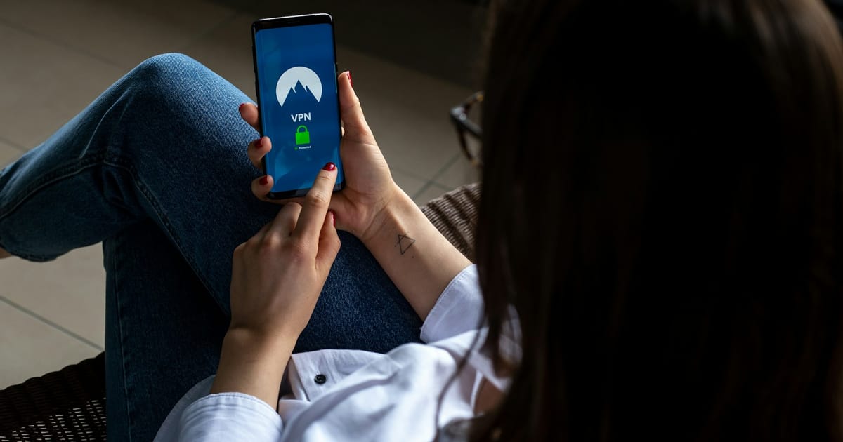 Una persona usa su celular junto a una computadora.