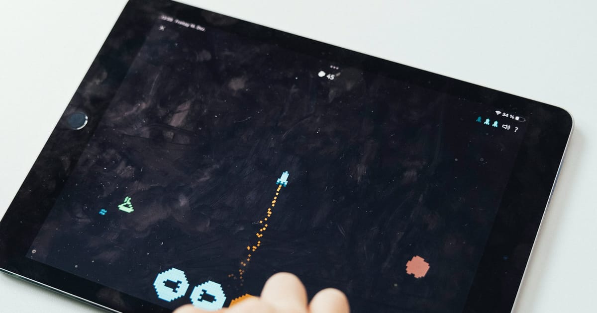 Una tableta sobre una mesa con un videojuego de gráficos sencillos en pantalla.