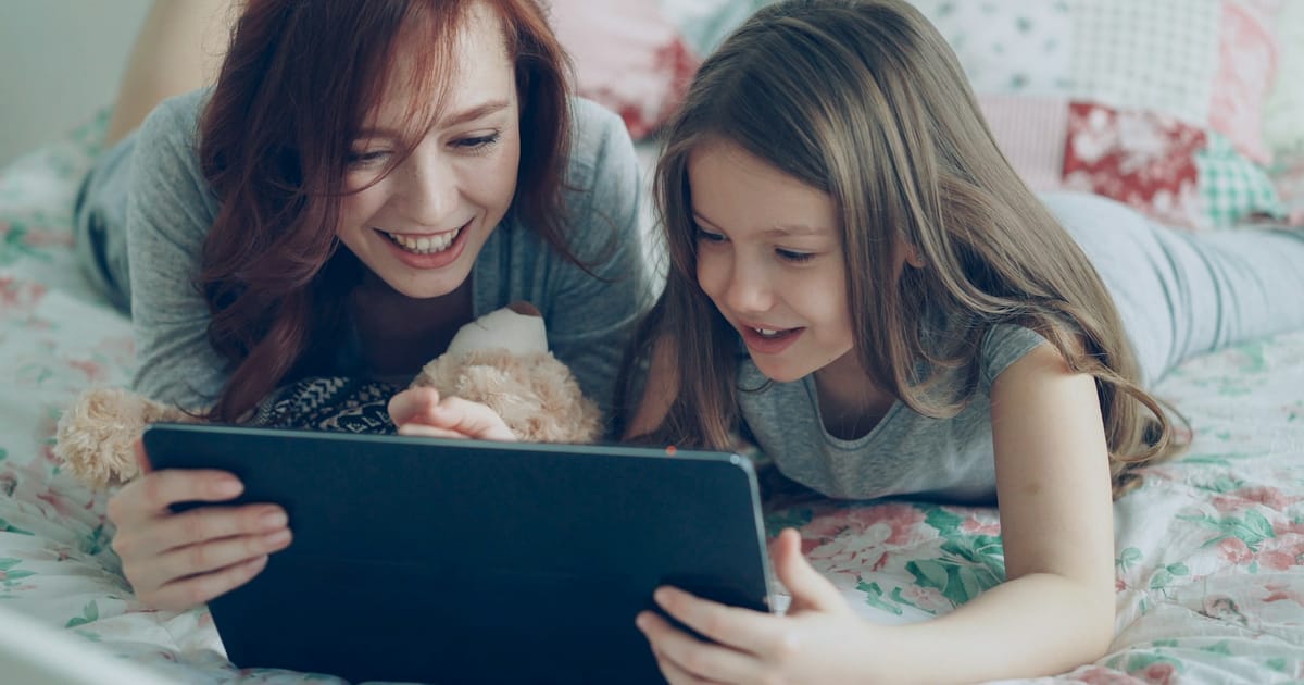 Una madre y su hija observan juntas la pantalla de una tablet.